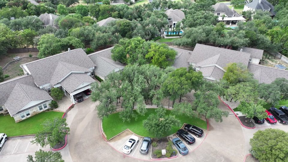 Aerial view of the two Bee Cave buildings, the circular drive between them, and the live oak canopy