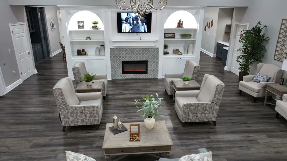Living room at Bee Cave with a tiled fireplace, arched white built in shelving, and armchairs around a low table