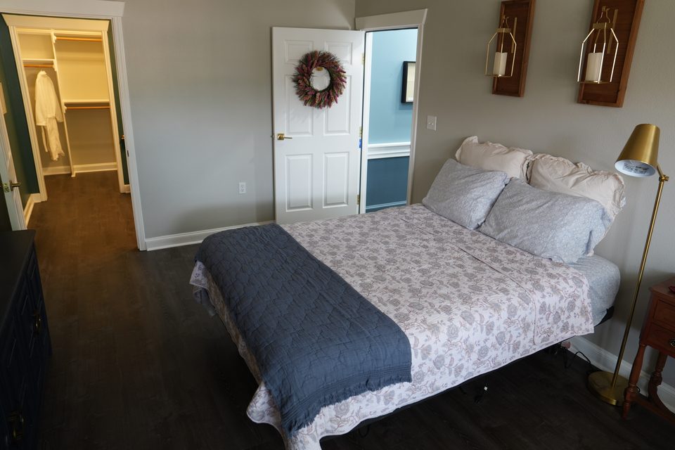 Private suite at Bee Cave with a brass floor lamp beside the bed and the closet door standing open