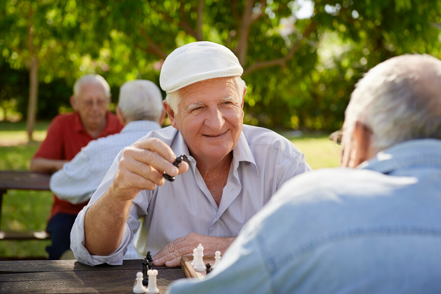 A couple of seniors enjoying a game of chess in a park.